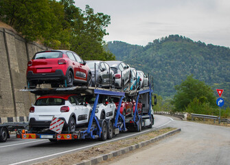 Naklejka premium Car transporter transports new cars to the showroom. Cars arranged on two levels. Cars of different colors.No logo or brand.