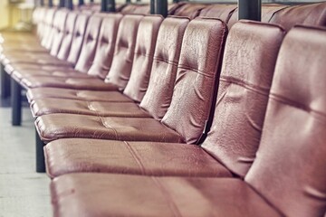 Row of empty comfortable soft chairs covered with brown leather in light spacious conference hall before event close view