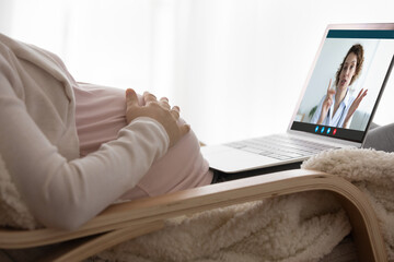Pregnancy and telehealth. Close up of young female touch baby bump sit by laptop pc get gp attending physician advices by video call. Pregnant woman communicate to doctor using online health service