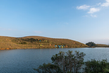 In the lake on the grassland, people set up tents by the lake