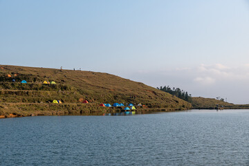 In the lake on the grassland, people set up tents by the lake