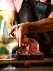 Fototapeta na wymiar Raw beef steak, close up. Chef is holding fresh raw steak, on a wooden cutting board.