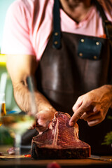 Raw beef steak, close up. 
Chef is holding fresh raw steak, on a wooden cutting board.