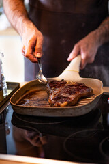 Raw beef steak, close up. 
Chef is holding fresh raw steak, on a wooden cutting board.