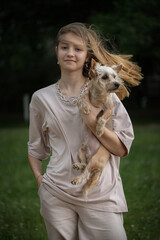 Portrait of a young beautiful blonde girl with a Yorkshire terrier in her arms.