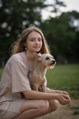 Portrait of a young beautiful blonde girl with a Yorkshire terrier in her arms.