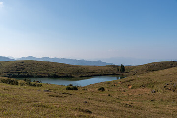 Obraz premium The full view of the natural lake on the grassland, with blue sky, clear water and yellow grass