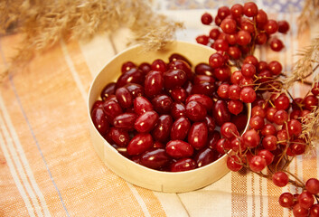 Organic autumn berries of viburnum and dogwood in wooden bowl in cozy home interior. Healthy food for tea, compote and jam concept. Top view background, copy space