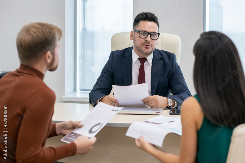 Poster confident mature businessman with paper discussing financial points or data with his two subordinate