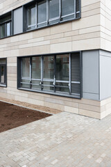 Construction and improvement of the local area. Lawn preparation and sowing with grass. Ground floor of an apartment building and beige ventilated facade. Porcelain stoneware on the wall of the house.