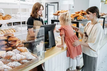  Mum with her daughter buying some pastry in a bakery shop. © zzzdim