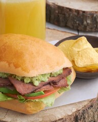 Sánduche de roast beef con salsa de guacamole, papas fritas y jugo de naranja acercamiento