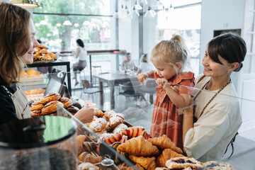 Spoiled with choice little girl picking herself some croissants in a bakery.