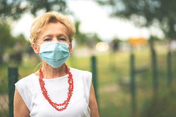 Portrait of a beautiful Blonde Woman Wearing a Mask.
Senior woman wearing medical face mask during Covid-19 pandemic, outdoor.
