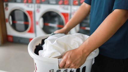 Man doing launder holding basket with dirty laundry of the washing machine in the public store. laundry clothes concept