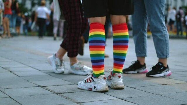 Summer rally activists and peaceful demonstrator on non-violent pride LGBT parade standing with rainbow knee socks and sneakers on city streets. Gays, lesbians and feminists crowded demonstration.