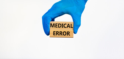 Medical error symbol. Doctor hand in blue glove holds wooden blocks with words Medical error, beautiful white background. Medical error concept.