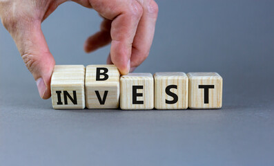 Best invest symbol. Businessman turns wooden cubes and changes the word 'invest' to 'best'. Beautiful grey background. Business and best invest concept. Copy space.