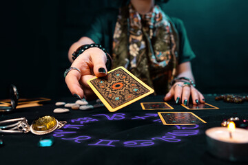 Fortune-telling on cards. The fortune teller hands over a Tarot card. The zodiac circle surrounds on the table. The concept of divination, astrology and esotericism - obrazy, fototapety, plakaty