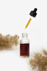 Fototapeta premium Glass cosmetic bottle with pipette with oil on white background.