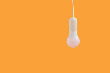 Hanging light bulb isolated on orange background