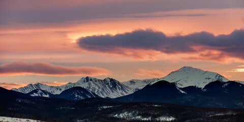 Sunset behind a snow covered mountain - obrazy, fototapety, plakaty