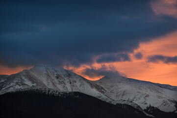 Orange sunset behind foreground clouds and the Continental Divide near Winter Park, Colorado