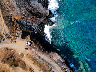 Aerial view of rocks and sea waves in a volcanic landscape with lava