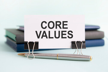 a white card with content marketing text stands on paper clips on a desk against the light blue background, selective focus