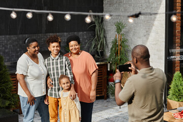 Portrait of happy African-American family posing for photo at terrace outdoors, copy space