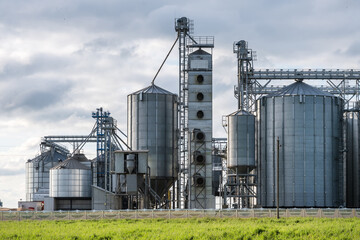Modern Granary elevator and seed cleaning line. Silver silos on agro-processing and manufacturing plant for storage and processing drying cleaning of agricultural products, flour, cereals and grain.