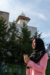 Portrait of cheerful muslim woman wearing a hijab isolated with mosque background. Vertical view of...