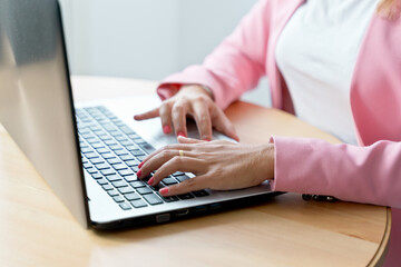 Close up of unrecognizable caucasian woman working with keyboard at home. Horizontal detail of woman hands typing on computer indoors. Online working and technology concept.