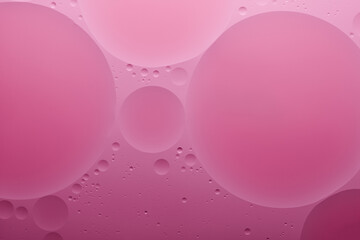 Water and oil, color abstract background based on pink, rose color circles and ovals, macro abstraction, real photo.