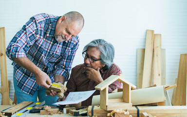 Two senior mixed race diverse happy retired old male woodworkers or carpenters wearing check...