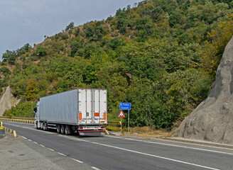 Truck transporting goods moving on a beautiful road near the mountain. Truck carrying various goods. No logo or brand.