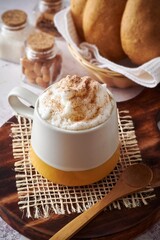 Mochaccino con extra crema y polvo de chocolate, con pan casero sobre tabla de madera rustica 