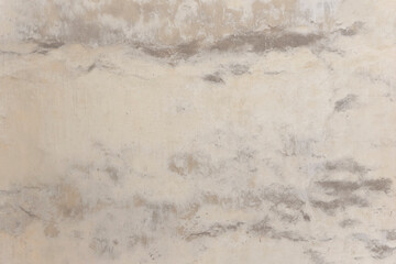 Shabby wall of an old house with uneven crumbling plaster. Yellow-gray abstract texture.