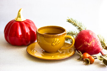 Obraz na płótnie Canvas Small yellow ceramic cup with black coffee on saucer stands on white table top view. Autumn leaves, rosehip berries, spruce branch, red pear. Red jack o lantern pumpkin, Halloween, Thanksgiving day.