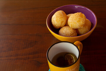 Uma caneca de chá e uma vasilha de pães de queijo.