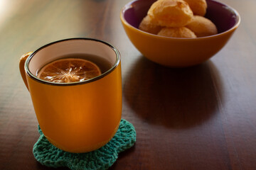 Uma caneca de chá e uma vasilha de pães de queijo.