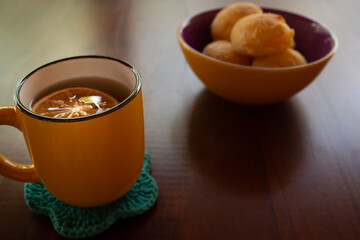 Uma caneca de chá e uma vasilha de pães de queijo.
