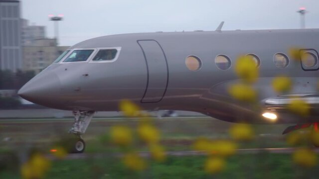 Business jet is taxiing on the runway after landing ay dusk. Side view
