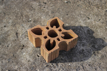 Red perforated air bricks with floral holes for building ventilation.