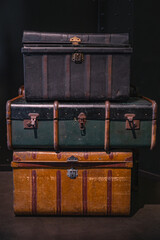 Selective focus on pile of three vintage, old and warn travel suitcases or trunks on the floor. Retro style voyage.