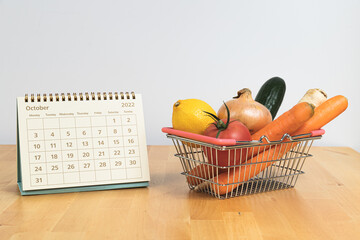October 2022 calendar and vegetables in shopping basket - symbol of prices and inflation