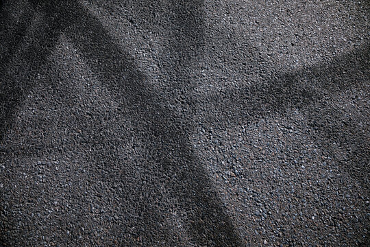 Tire tracks on dark grey asphalt with lines and curves, abstract street background