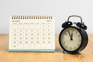 Fototapeta na wymiar October 2022 calendar and vintage clock on a wooden table