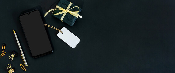 Black present with ribbon and label on black background. Black friday holiday in shops stores and shopping malls with sale and discount concept.