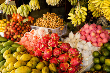 Phnom Penh, Cambodia: Colorful tropical fruit for sale in an open-air market includes bananas, rambutan, papayas, oranges, dragon fruit, and mangos.